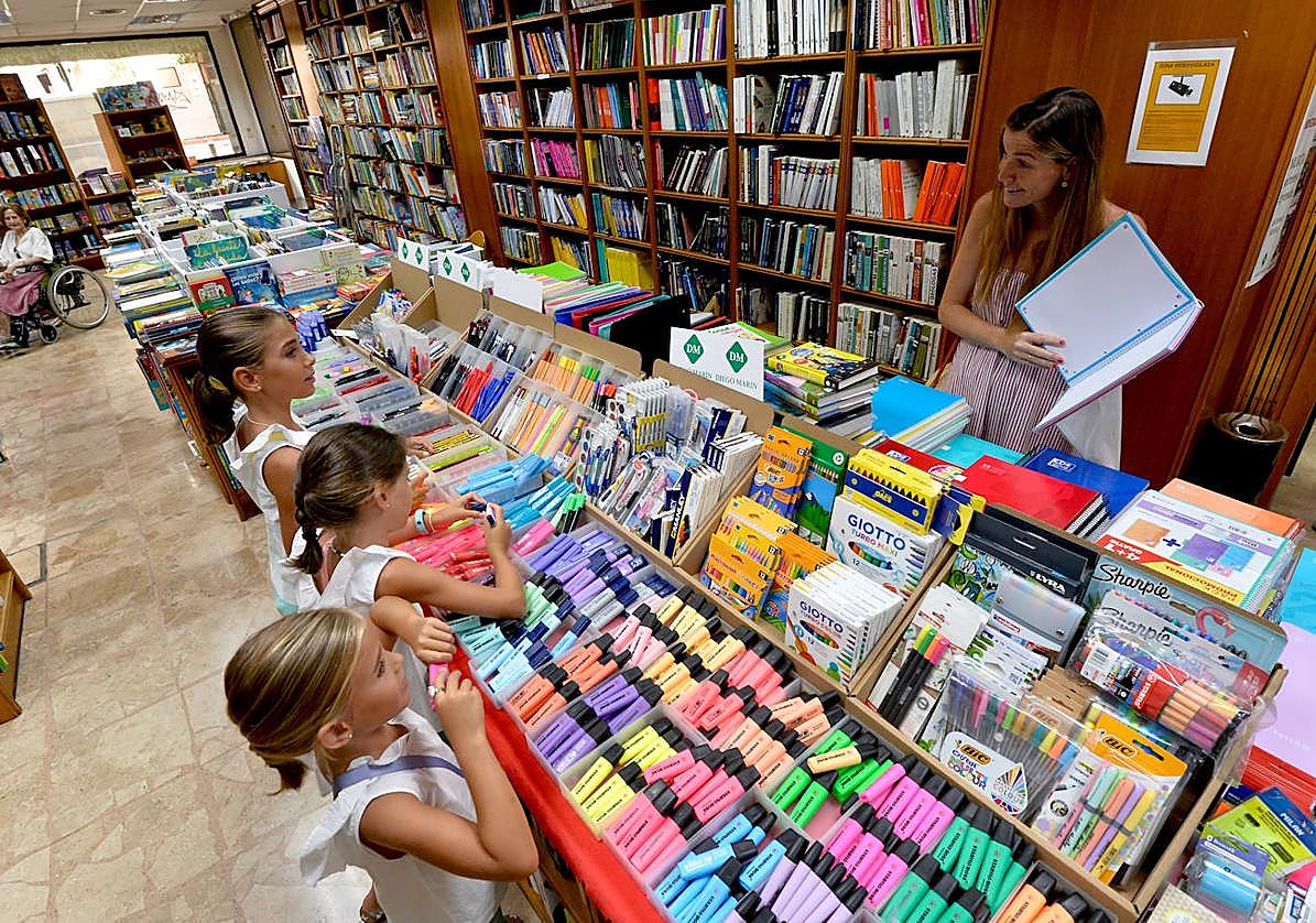 Pilar Molina Guillén muestra material escolar a sus tres hijas en la librería Diego Marín.