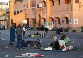 Turistas y locales despiertan tras pasar la noche en una plaza al raso en Marrakech este sábado.