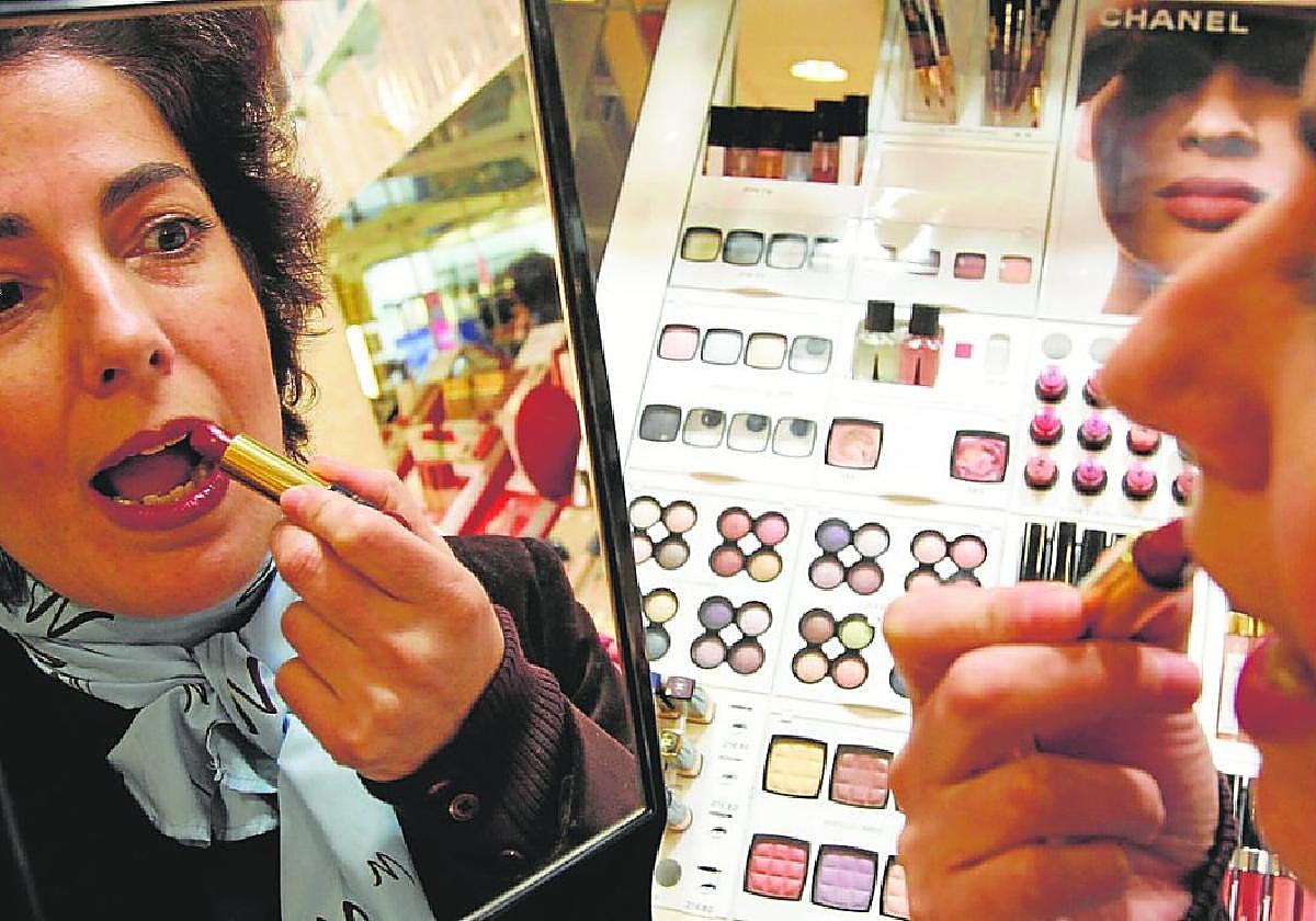 La gerente de una tienda de cosméticos parisina prueba un pintalabios; Francia es donde más crece la presencia de cosméticos murcianos.