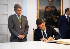 El president Carlos Mazón firma en el libro de visitas del Ayuntamiento de Orihuela en presencia del alcalde, Pepe Vegara.