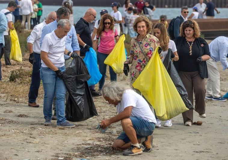 La Reina Sofía sujeta una bolsa mientras Pedro García, director de Anse, recoge algunos residuos agachado.