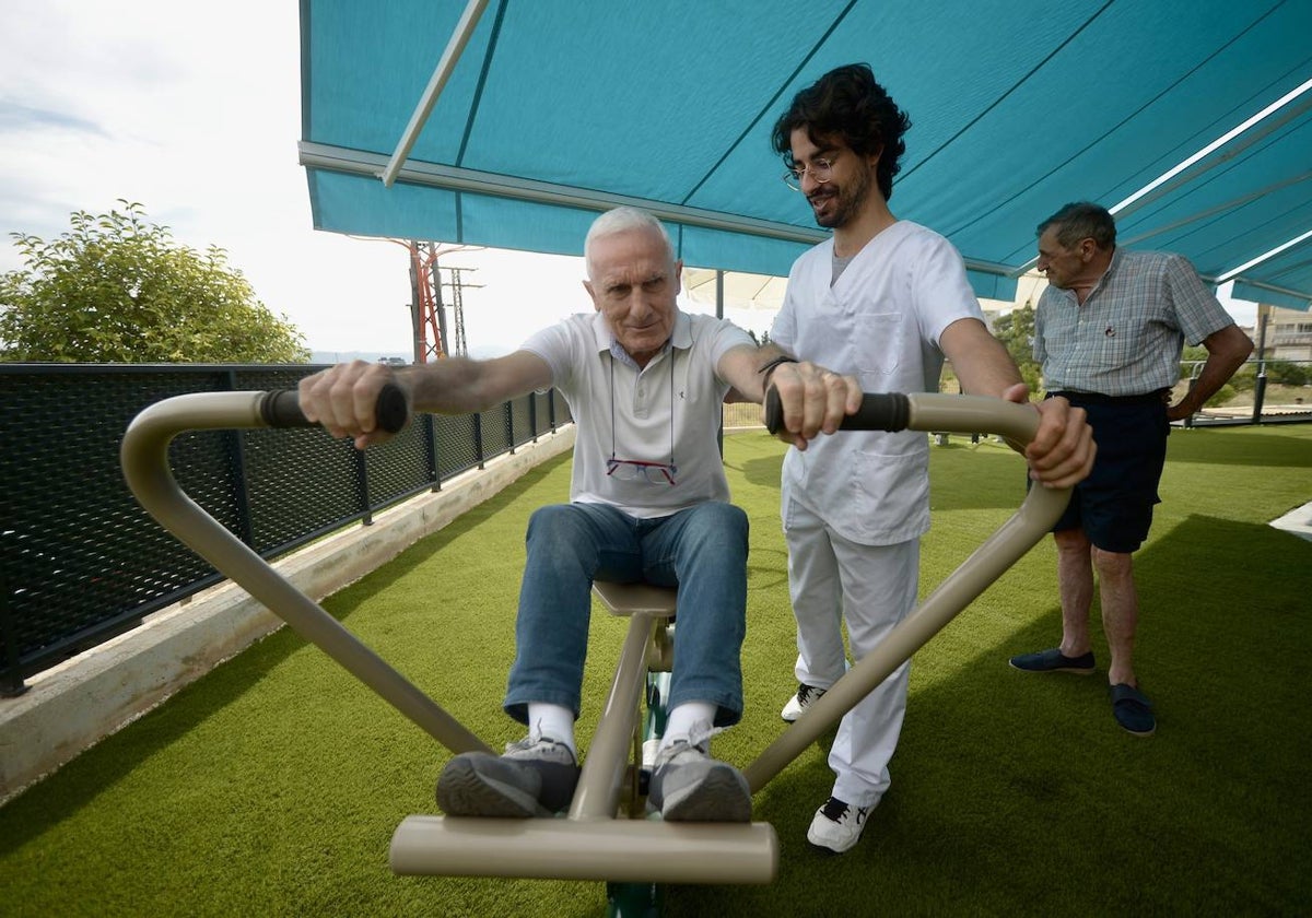 Silvio, usuario de Afamur, estrena uno de los nuevos aparatos de gimnasia instalados en el centro de día de la asociación. Junto a él, el fisioterapeuta Javier Lucas.