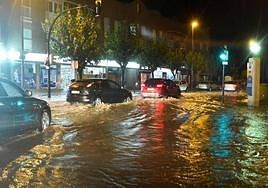 Vehículos circulando por una carretera inundada en la zona de la rambla de Churra.