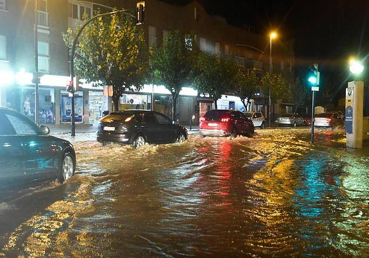 Vehículos circulando por una carretera inundada en la zona de la rambla de Churra.