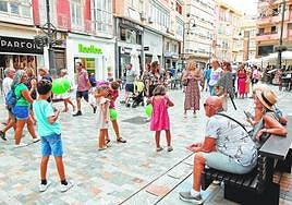 Decenas de personas pasean por la Puerta de Murcia el viernes festivo, junto a las terrazas de varios bares con mesas vacías.