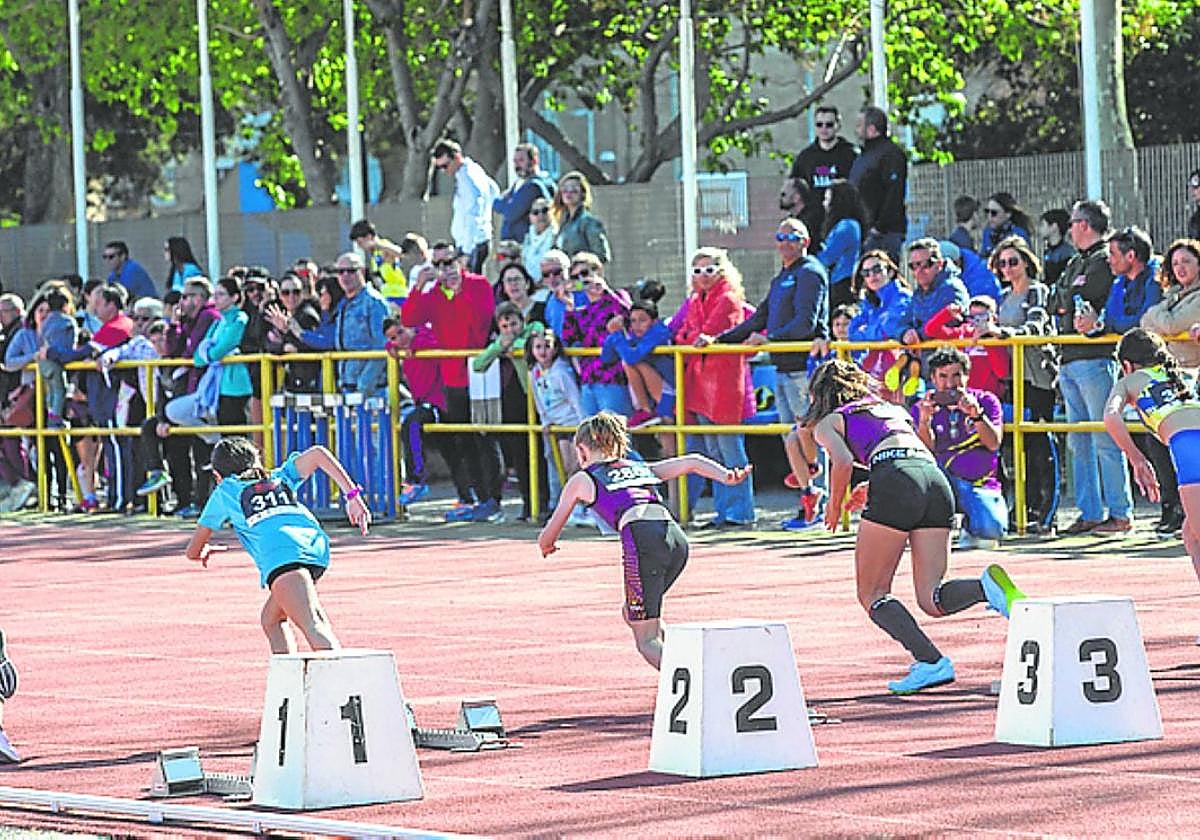 El público, de pie, sigue una prueba en la pista.
