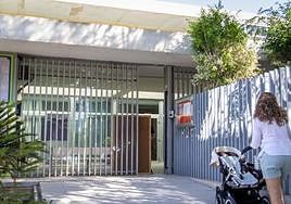 Un docente retira el panel de corcho que mantiene abierta la puerta averiada del centro.