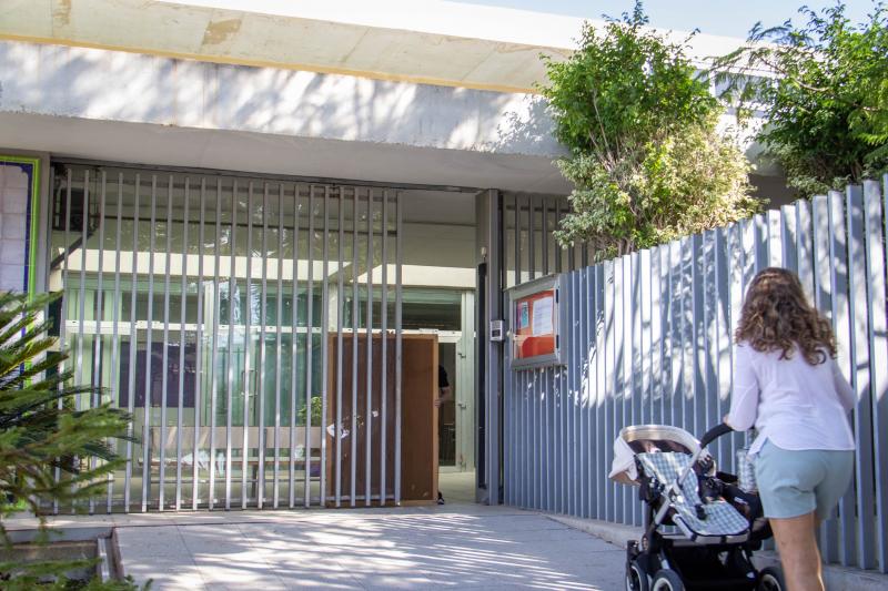 Un docente retira el panel de corcho que mantiene abierta la puerta averiada del centro.