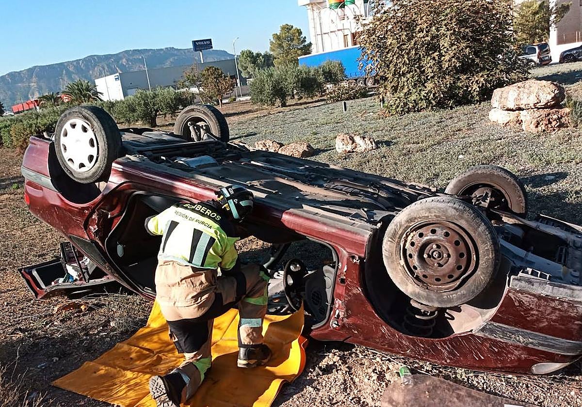 Un bombero trabaja en el coche volcado de Alhama.