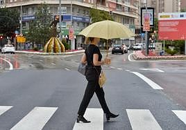 Una viandante con un paraguas por el centro de Murcia, en una imagen de archivo.