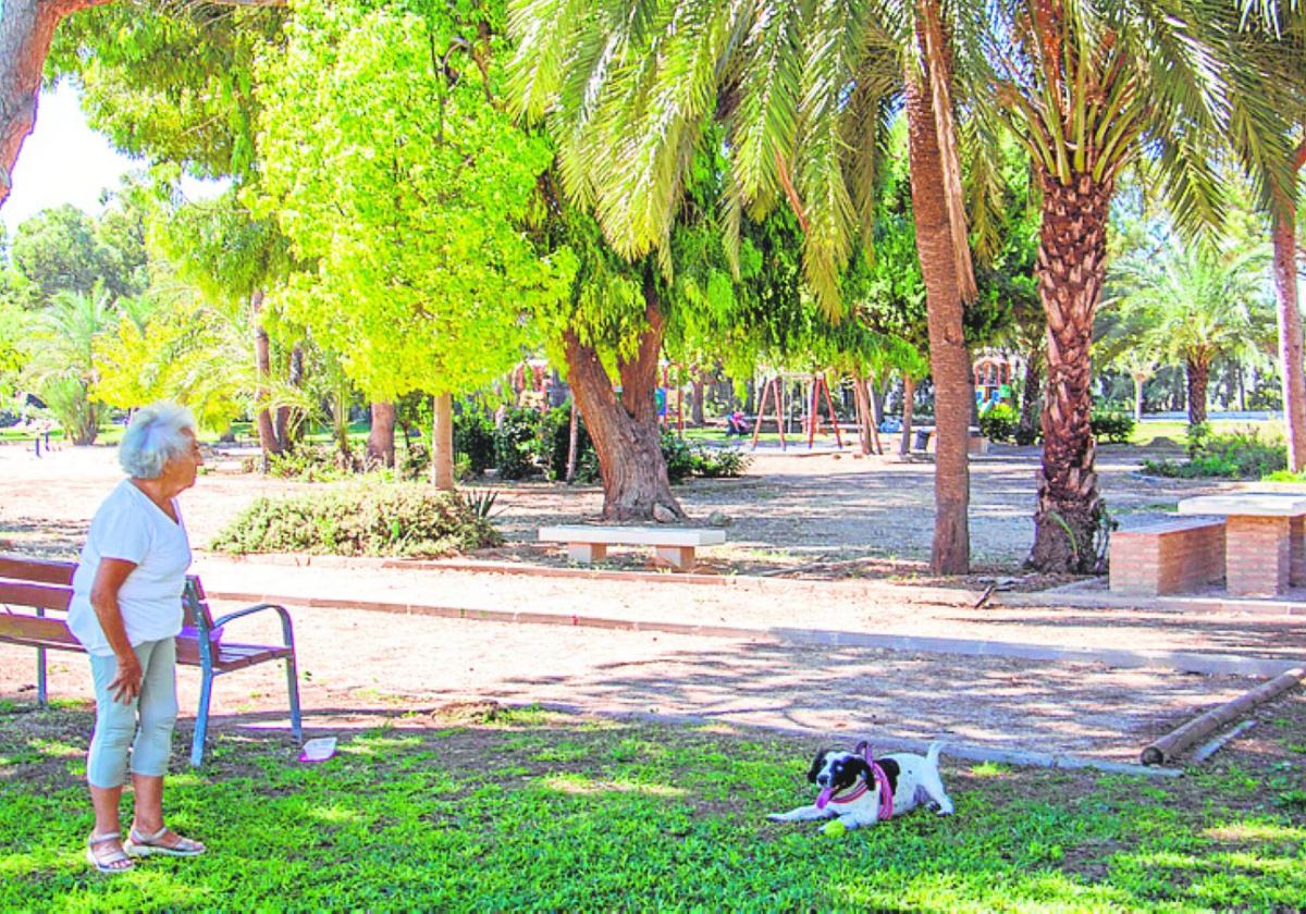 Una mujer pasea a su perro por un parque de La Zenia.