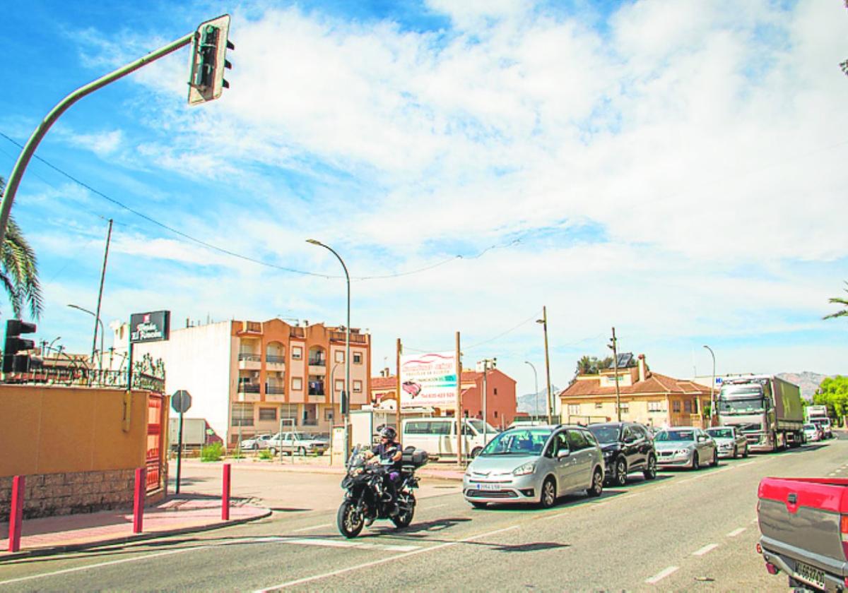Una hilera de coches, frente al semáforo y sobre la parrilla.