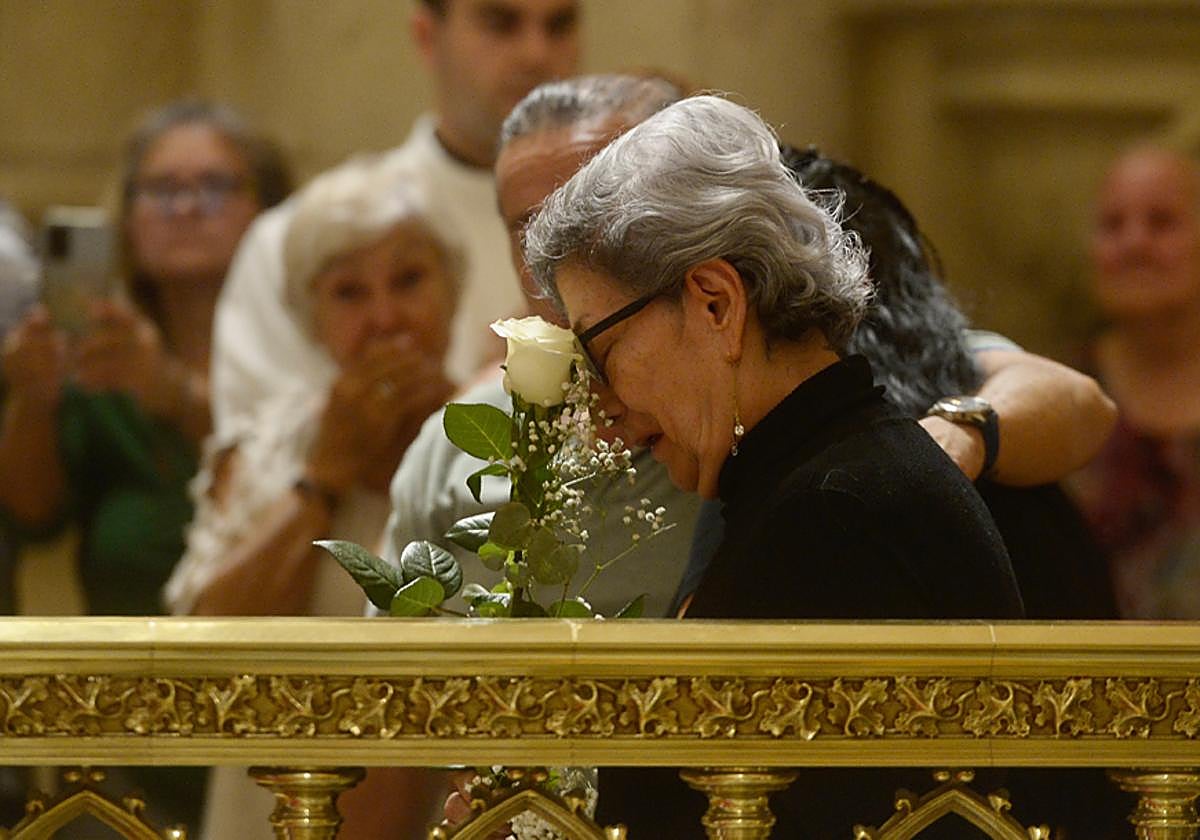 La familiar de uno de los fallecidos llora desconsolada con la rosa blanca que le entregó el obispo.