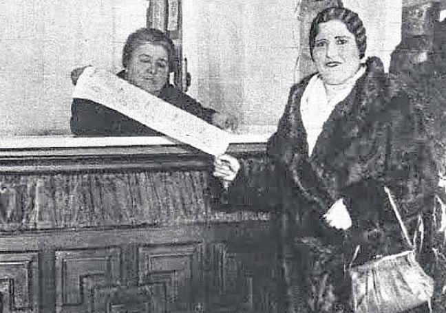 Doña Manolita, tras el mostrador, junto a una clienta en su administración de lotería.