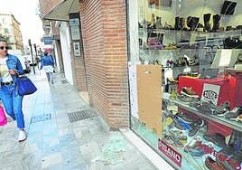 Una joven pasa junto al escaparate reventado de la tienda de zapatos de la calle Maestro Alonso, ayer.