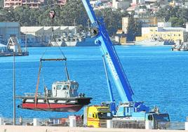 Una grúa pone a flote la primera empujadora, en unas maniobras realizadas en el muelle de La Curra.