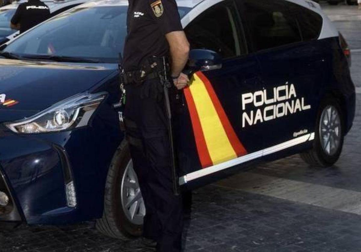 Un agente de la Policía Nacional junto a un coche patrulla, en una imagen de archivo.