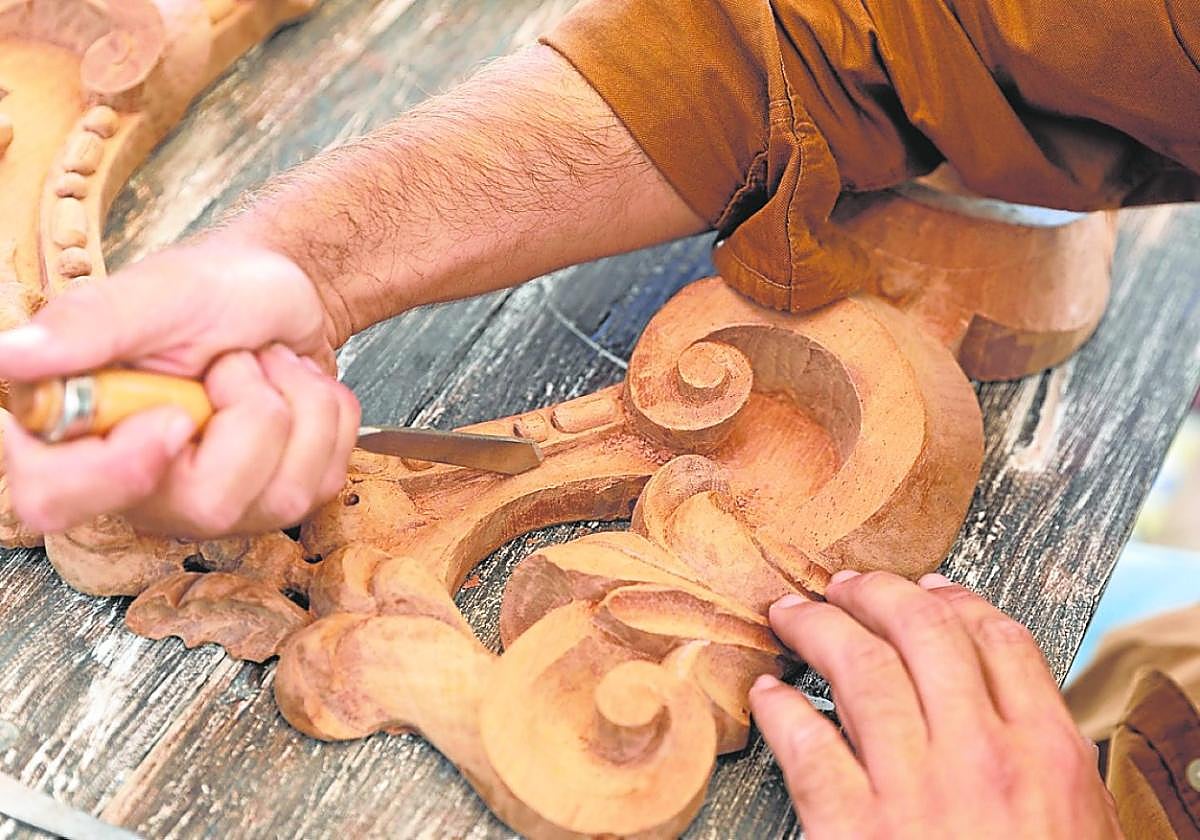 Un maestro artesano trabaja sobre una pieza de madera ornamental.