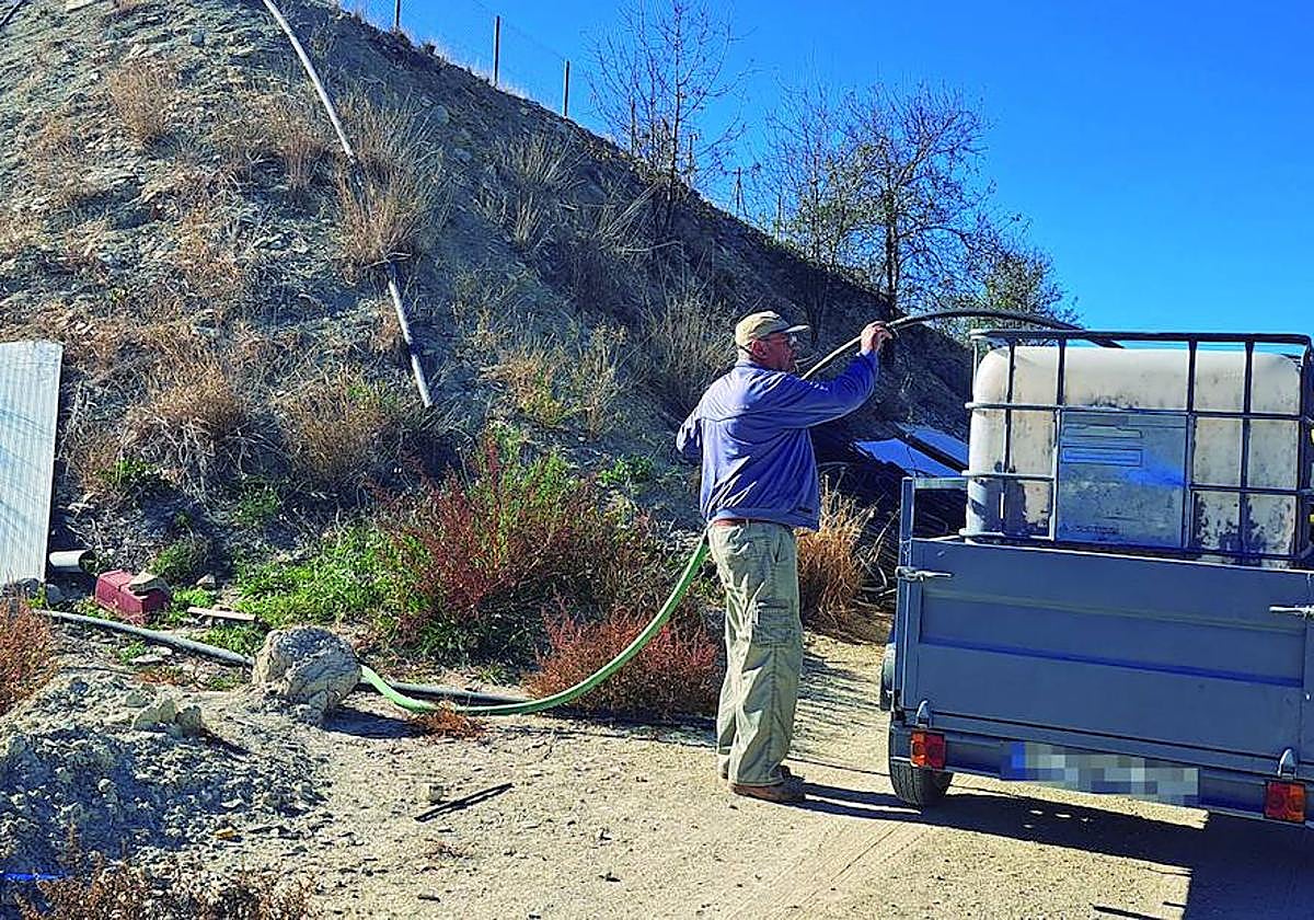 Antonio Palazón, vecino de El Boquerón, llena el depósito de 1.000 litros en una balsa de riego para llevarlo a su casa.