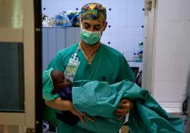 Un anestesista traslada a un niño recién operado desde el quirófano hasta la sala de reanimación.