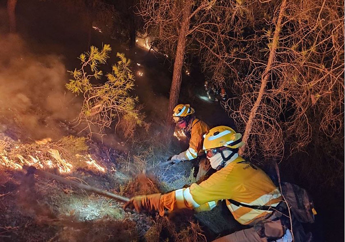 Dos brigadistas forestales desbrozan vegetación en uno de los dos flancos del incendio en el Valle de Murcia, el 29 de agosto.