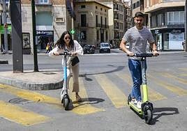 Dos personas circulan con patinetes alquilados en una imagen de archivo.