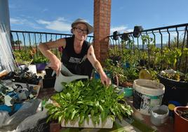 La londinense Sally Johnstone, que sufre ecoansiedad desde hace siete años, riega las plantas en el balcón de su casa de La Arboleja.