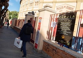 Un viandante pasa junto al cartel de la macrofiesta anunciada en la Plaza de Toros de Murcia.