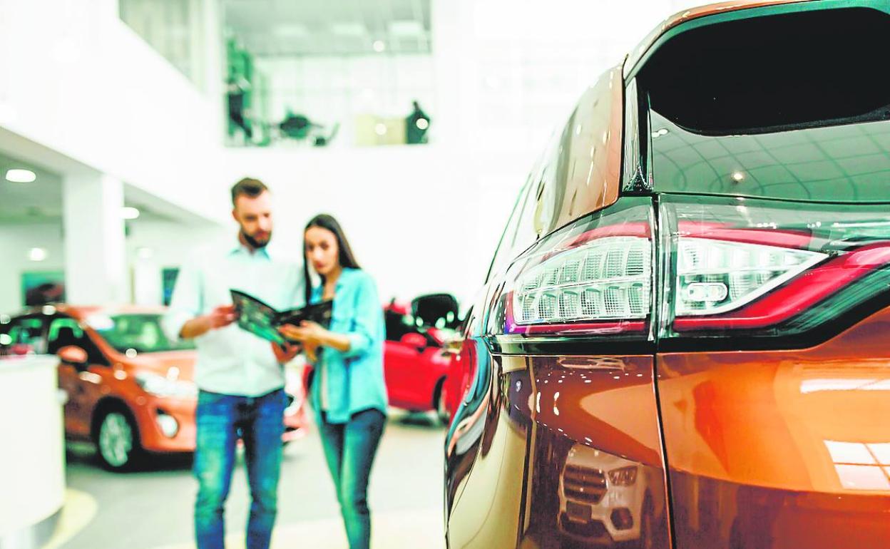 Una pareja consulta un folleto en el interior de un concesionario.