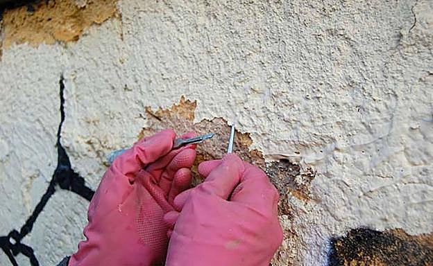 Una restauradora levanta la pintura con bisturí y pinzas. 