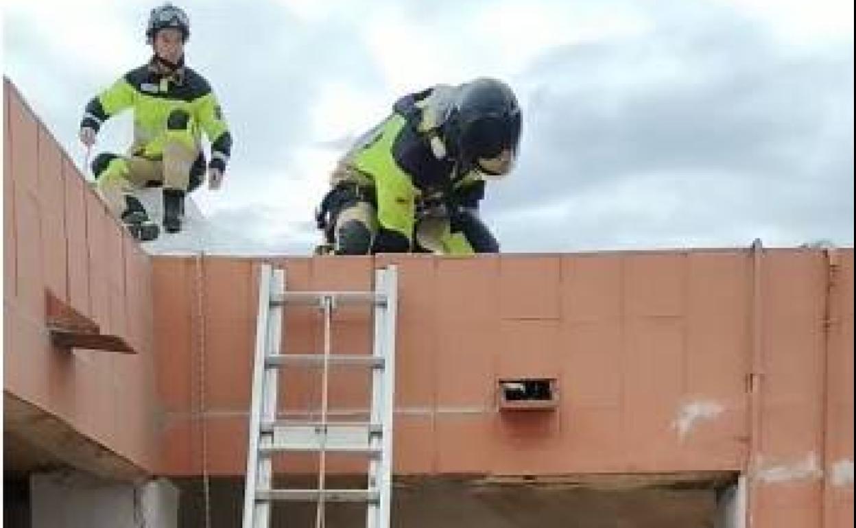 Bomberos en el lugar del suceso, tratando de acceder mediante una escalera.