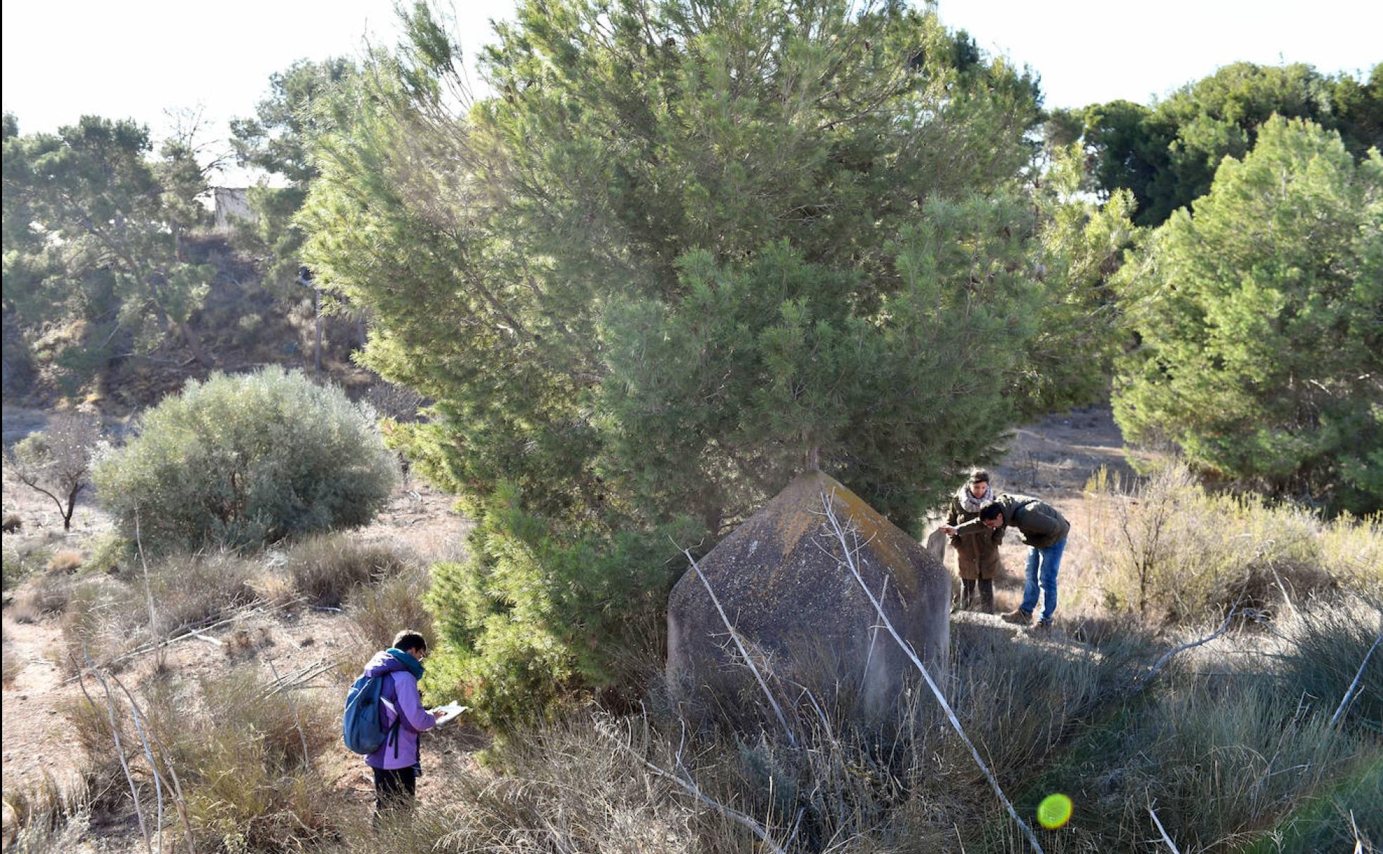 El equipo observa el interior del aljibe y Encarna Rodríguez (i) puntea en el mapa su ubicación. 