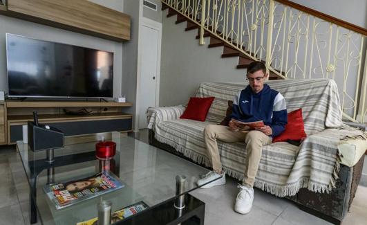Adrián Rubio, solicitante del Bono Alquiler Joven, leyendo una revista en el dúplex donde reside en el municipio de Las Torres de Cotillas. 