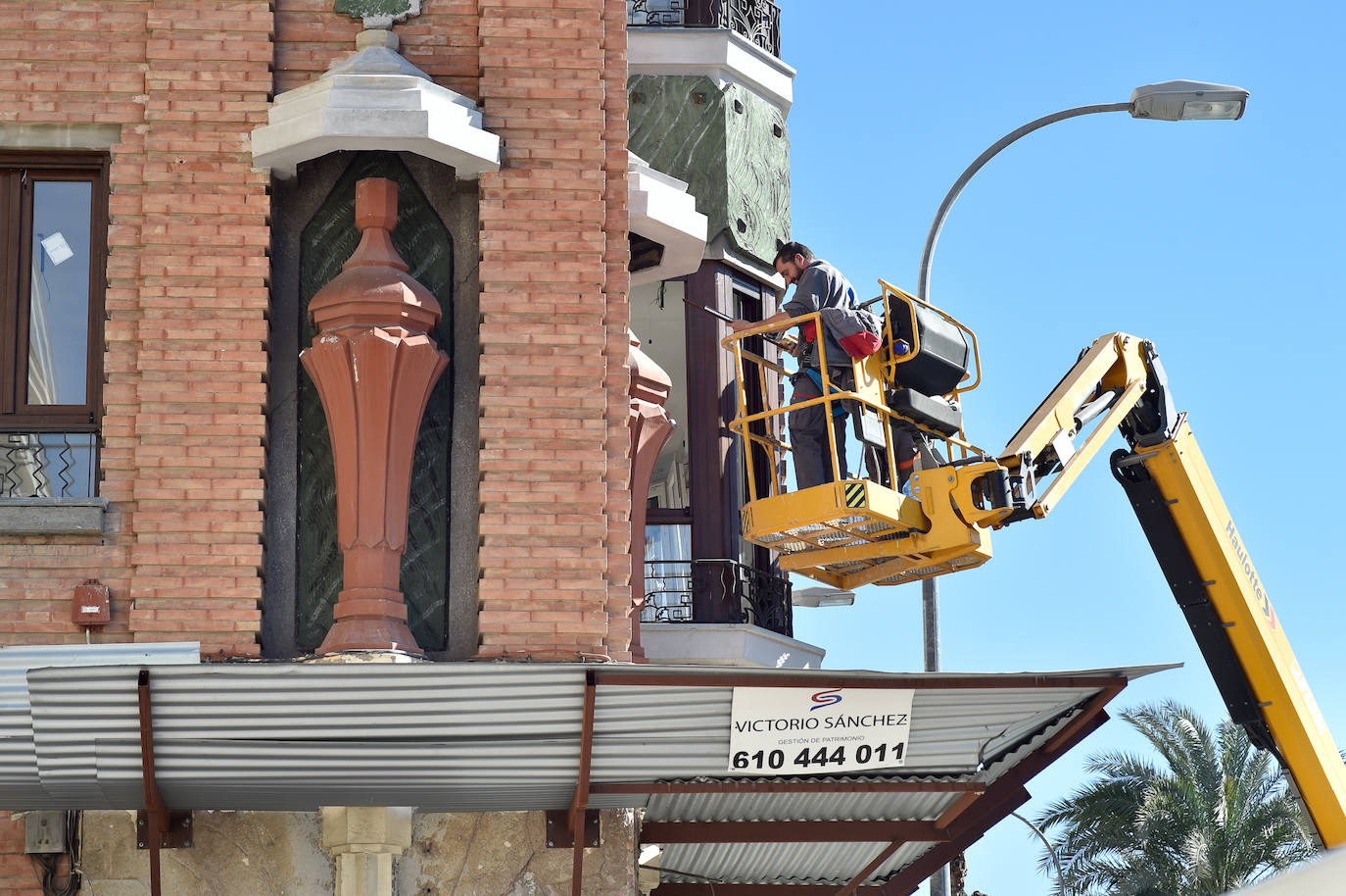 Unos operarios, durante las labores de restauración de la fachada de la Casa de los Jarrones (Murcia).