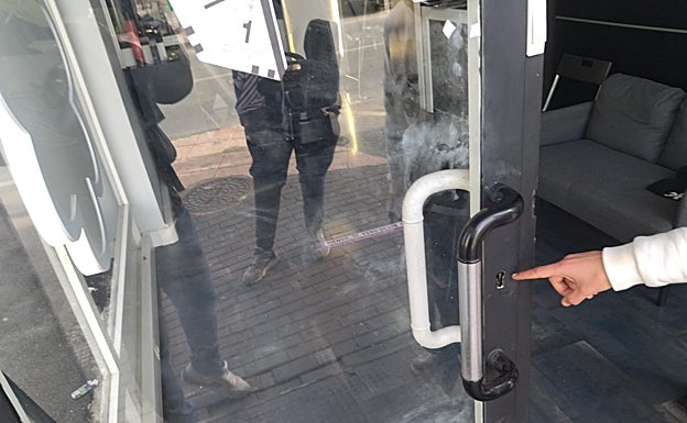 El propietario de la barbería muestra la cerradura forzada de la puerta a su negocio.