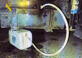 Una manguera conecta un depósito de combustible de un vehículo con una garrafa.