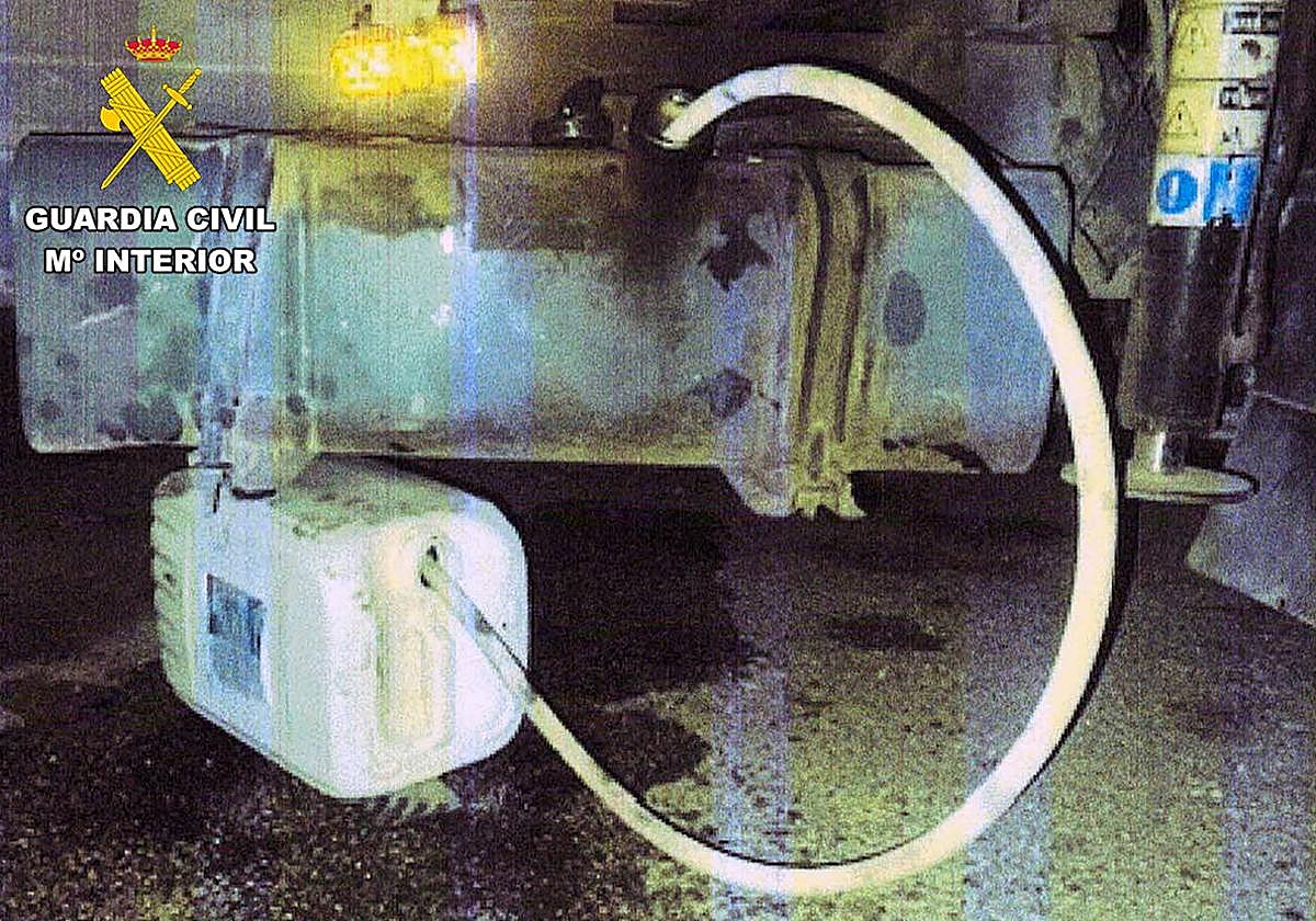 Una manguera conecta un depósito de combustible de un vehículo con una garrafa.