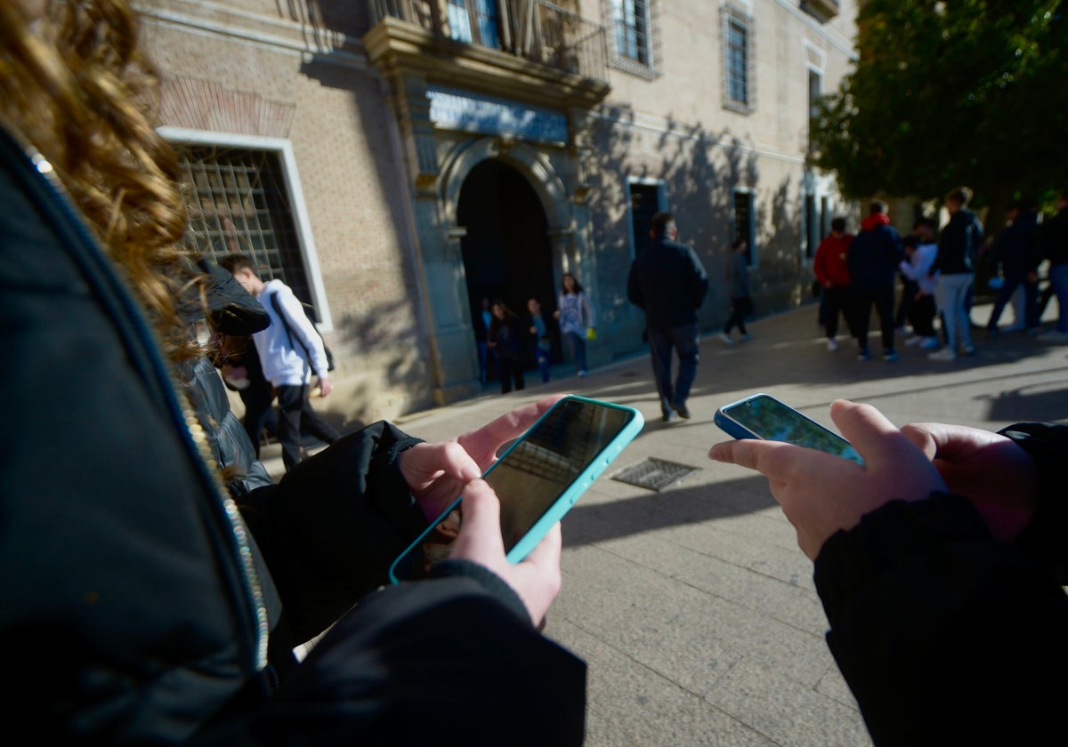 Dos estudiantes consultan su teléfono a las puertas del IES Licenciado Cascales de Murcia.