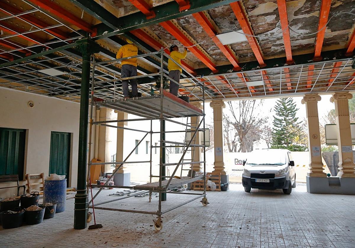 Dos albañiles arreglan el techo del vestíbulo de entrada a la zona escolar de la Casa del Niño, que fue precintada por la caída de cascotes y el peligro de derrumbe.