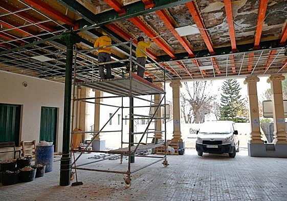 Dos albañiles arreglan el techo del vestíbulo de entrada a la zona escolar de la Casa del Niño, que fue precintada por la caída de cascotes y el peligro de derrumbe.