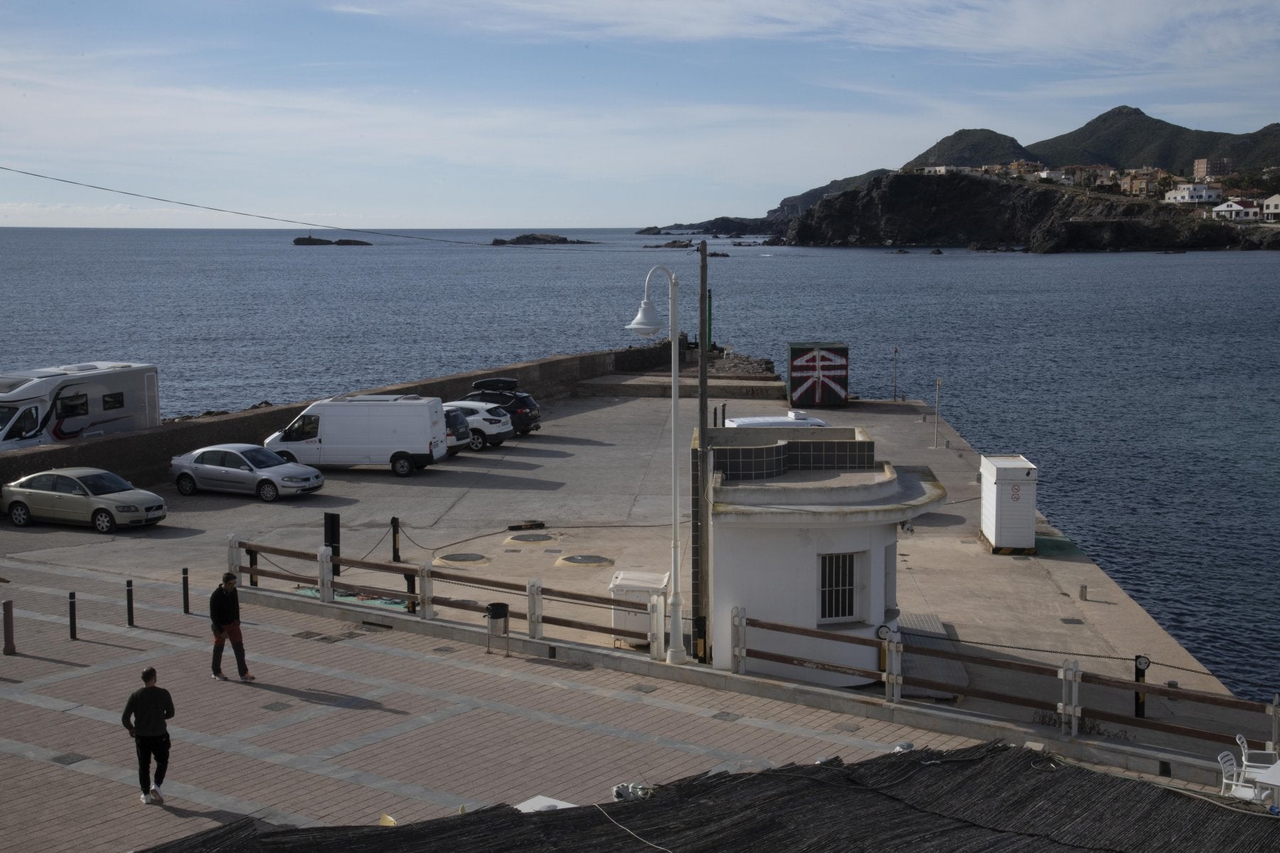 Dos personas pasean por la bocana de Cabo de Palos, al final del conocido Muro de la Sal.