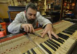 Víctor Javier Martínez revisa las teclas del piano del casino de Mazarrón; detrás, el bastidor y el arpa metálica del instrumento.