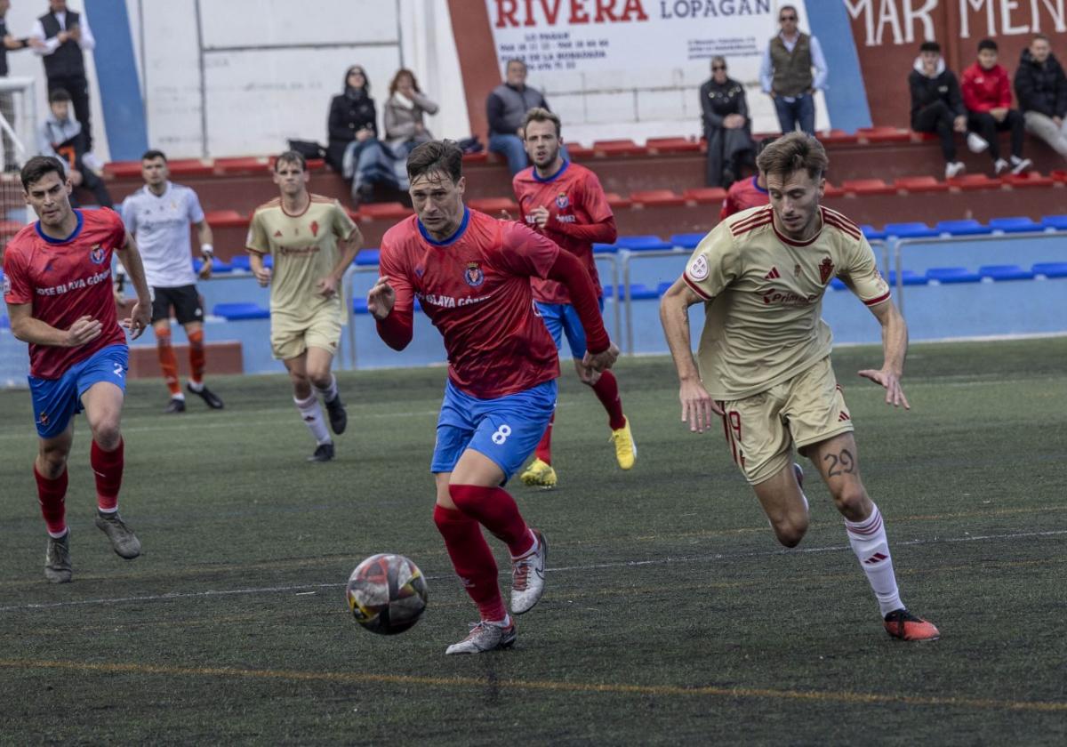 El local Britos y el visitante Ángel García corren en busca de un balón dividido.