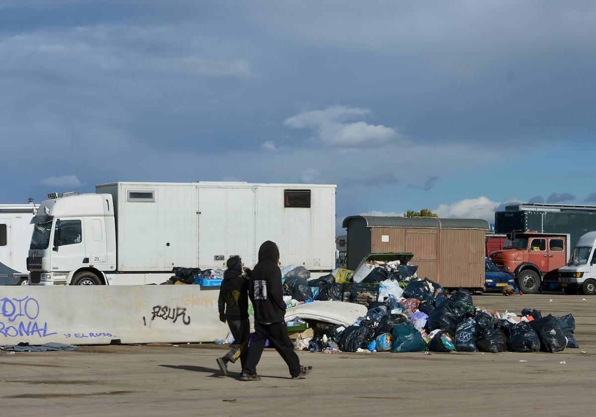 Dos personas caminan junto a un montón de basura el último día de la 'rave'.