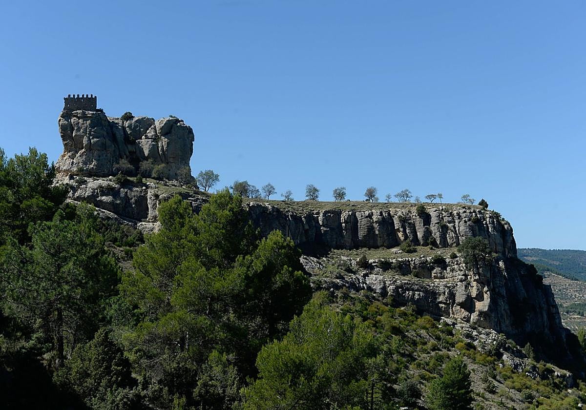 El castillo de Benizar desde el flanco oeste, con la muela coronada por la torre del homenaje y los almendros sobre la meseta.