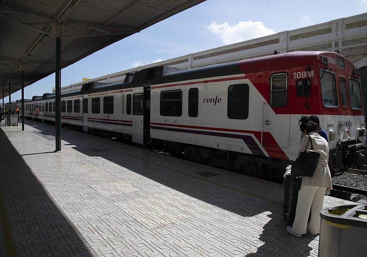 Una mujer con su maleta se prepara para subir al tren de cercanías.