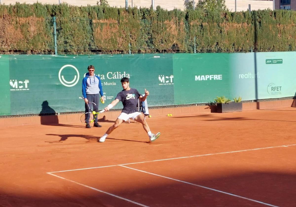 Carlos Alcaraz golpea la bola, observado por Juan Carlos Ferrero, este viernes en el Real Murcia Club de Tenis 1919.