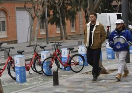 Dos viandantes pasan junto a una estación de MuyBici en los alrededores del Teatro Romea.