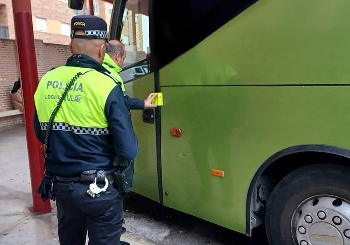 Dos agentes de la Policía Local de Mula, precintando un autobús interurbano.