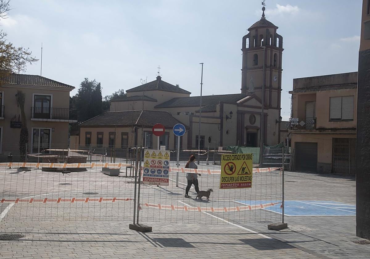 Una vecina pasea por la Plaza Manuel Zamora, ahora vallada casi al completo tras la colocación de los adoquines y la señalización.